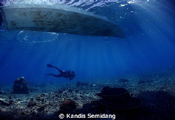 A diver passing under a boat by Kandis Semidang 